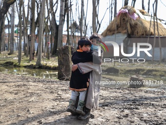 A boy carries her sister through a muddy road in Sopore district Baramulla Jammu and Kashmir India on 02 March 2022. (