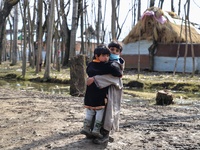 A boy carries her sister through a muddy road in Sopore district Baramulla Jammu and Kashmir India on 02 March 2022. (