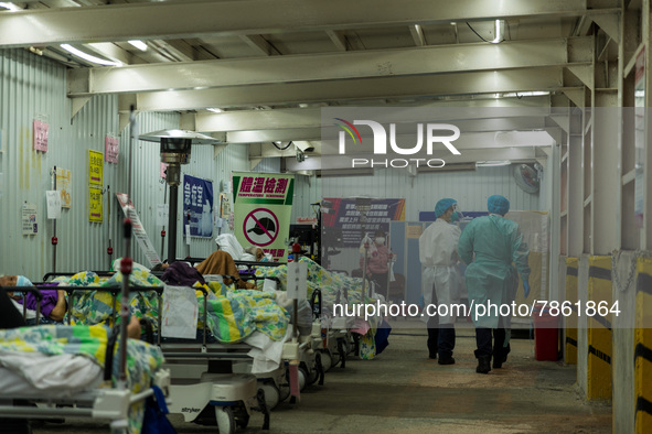 Nurses walk in front of COVID patients left outside the Accident & Emergency ward of United Christian Hospital in Kwun Tong, in Hong Kong, C...