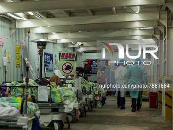 Nurses walk in front of COVID patients left outside the Accident & Emergency ward of United Christian Hospital in Kwun Tong, in Hong Kong, C...