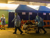 Paramedics in PPE perform CPR on a patient in cardiac arrest at the Accident & Emergency ward of Queen Elisabeth Hospital, transporting him...