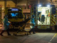 Paramedics in PPE bring back a stretcher to their ambulance, in Hong Kong, China, on March 04, 2022. (