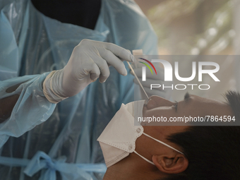 A health worker from Khlongtoey Deejung organisation takes a swab sample for a rapid antigen test, amid the coronavirus Omicron (COVID-19) p...