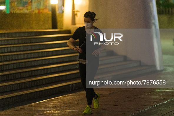 A masked jogger runs in front of the Central piers, in Hong Kong. Even strenuous physical activity without a mask is now punished with a 5,0...