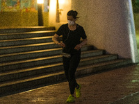 A masked jogger runs in front of the Central piers, in Hong Kong. Even strenuous physical activity without a mask is now punished with a 5,0...