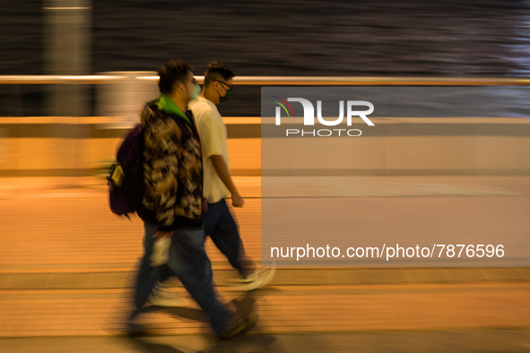 Masked people walk near Central piers in this panned shot, in Hong Kong, China, on March 6, 2022.  