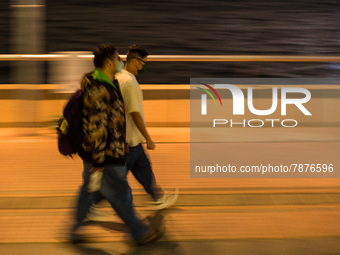 Masked people walk near Central piers in this panned shot, in Hong Kong, China, on March 6, 2022.  (