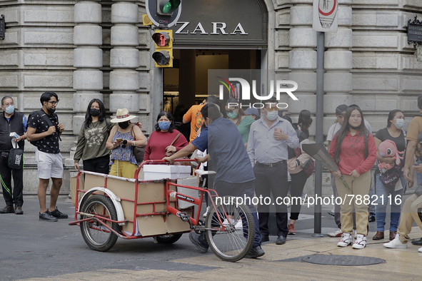 Passers-by outside a clothing shop in the Zócalo of Mexico City during the change to green epidemiological traffic light after recording a d...