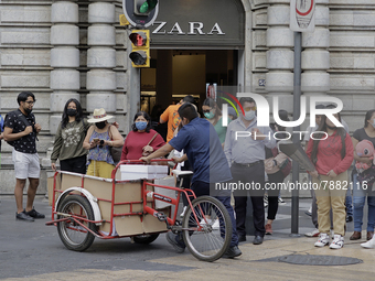 Passers-by outside a clothing shop in the Zócalo of Mexico City during the change to green epidemiological traffic light after recording a d...