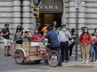 Passers-by outside a clothing shop in the Zócalo of Mexico City during the change to green epidemiological traffic light after recording a d...