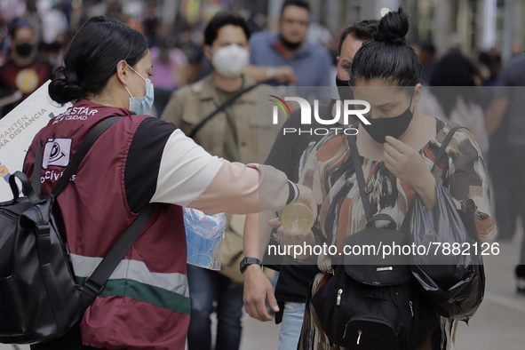 A person offers antibacterial gel to passers-by in Mexico City's Zócalo during the change to green epidemiological traffic light after recor...