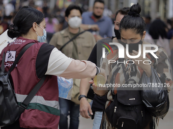 A person offers antibacterial gel to passers-by in Mexico City's Zócalo during the change to green epidemiological traffic light after recor...