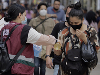 A person offers antibacterial gel to passers-by in Mexico City's Zócalo during the change to green epidemiological traffic light after recor...