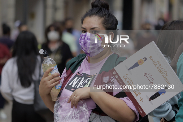 A woman offers antibacterial gel to passers-by in Mexico City's Zócalo during the change to green epidemiological traffic light after record...