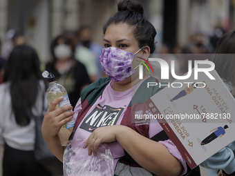 A woman offers antibacterial gel to passers-by in Mexico City's Zócalo during the change to green epidemiological traffic light after record...