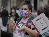 A woman offers antibacterial gel to passers-by in Mexico City's Zócalo during the change to green epidemiological traffic light after record...