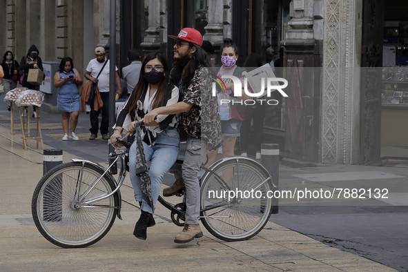 A couple on a bicycle in Mexico City's Zócalo during the change to green epidemiological traffic light after recording a decrease in hospita...