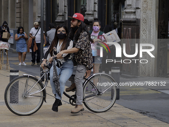 A couple on a bicycle in Mexico City's Zócalo during the change to green epidemiological traffic light after recording a decrease in hospita...