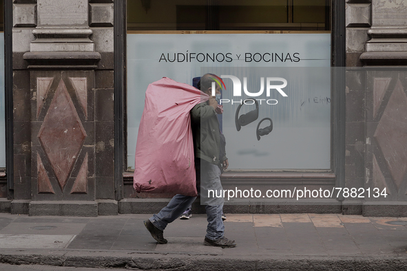 A pedestrian carries a bag in the Zócalo of Mexico City during the change to green epidemiological traffic light after recording a decrease...