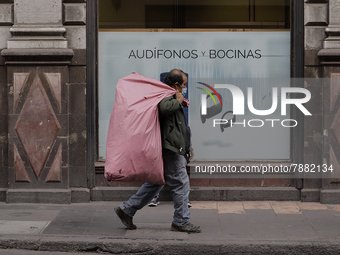 A pedestrian carries a bag in the Zócalo of Mexico City during the change to green epidemiological traffic light after recording a decrease...