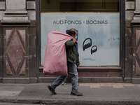 A pedestrian carries a bag in the Zócalo of Mexico City during the change to green epidemiological traffic light after recording a decrease...