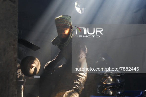 Worker works in dust environment inside in a utensil factory while sunrays enter through the rooftop in Dhaka, Bangladesh on March 08, 2022....