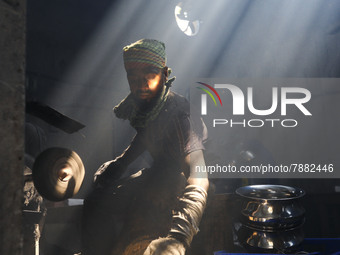 Worker works in dust environment inside in a utensil factory while sunrays enter through the rooftop in Dhaka, Bangladesh on March 08, 2022....