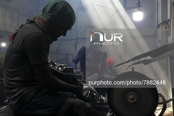 Worker works in dust environment inside in a utensil factory while sunrays enter through the rooftop in Dhaka, Bangladesh on March 08, 2022....