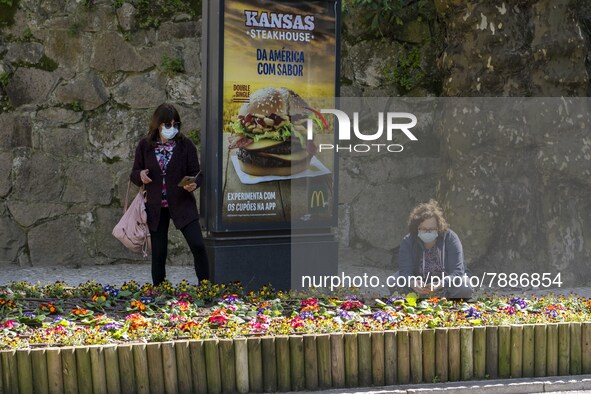 People wearing protective masks are seen picking some flowers around a street in Sintra. 28 February 2022. According to the General Health D...