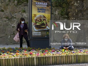 People wearing protective masks are seen picking some flowers around a street in Sintra. 28 February 2022. According to the General Health D...