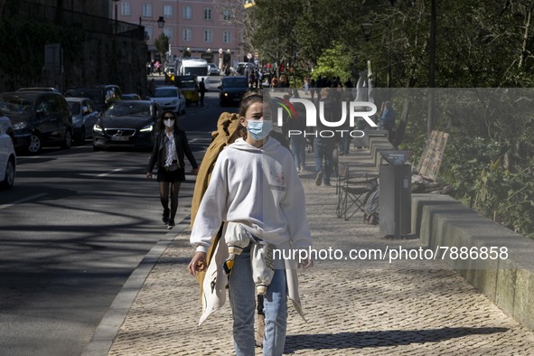 A woman wearing a protective mask is seen walking near a monument in the surroundings of a street in Sintra. 28 February 2022. According to...