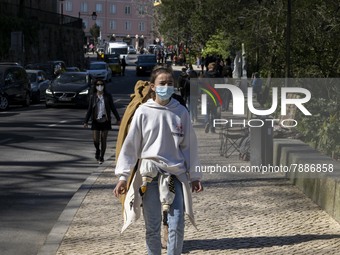 A woman wearing a protective mask is seen walking near a monument in the surroundings of a street in Sintra. 28 February 2022. According to...