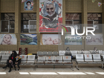 Social distancing signs are pictured on the chairs as mothers and their kids sit under a huge portrait of the former commander of the Islami...