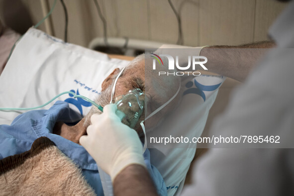 An Iranian nurse wearing a protective suit helps a patient to use oxygen at a COVID-19 ward in a hospital in the holy city of Qom 145Km (90...