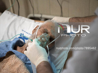 An Iranian nurse wearing a protective suit helps a patient to use oxygen at a COVID-19 ward in a hospital in the holy city of Qom 145Km (90...