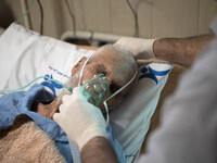 An Iranian nurse wearing a protective suit helps a patient to use oxygen at a COVID-19 ward in a hospital in the holy city of Qom 145Km (90...