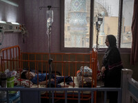 An Iranian mother stands next to her 9-year-old son with autism who is infected by COVID-19 as well, at a new coronavirus disease ward in a...