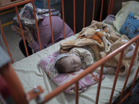 An Afghan mother sits next to her 5-mounth-old kid who is infected by COVID-19, at a COVID-19 ward in a children hospital in the holy city o...