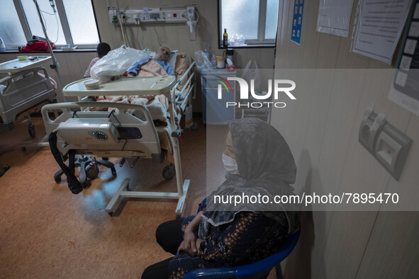 Relative of an Iranian elderly man who is infected by COVID-19, wearing a protective face mask while sitting next to her patient hospital be...