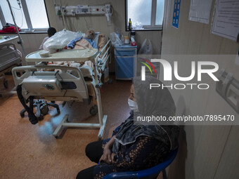 Relative of an Iranian elderly man who is infected by COVID-19, wearing a protective face mask while sitting next to her patient hospital be...