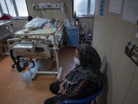 Relative of an Iranian elderly man who is infected by COVID-19, wearing a protective face mask while sitting next to her patient hospital be...