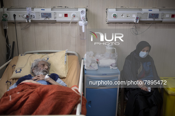 Relative of an Iranian elderly man who is infected by COVID-19, wearing a protective face mask while sitting next to her patient hospital be...