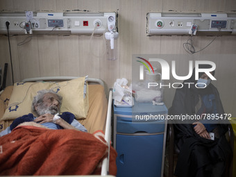 Relative of an Iranian elderly man who is infected by COVID-19, wearing a protective face mask while sitting next to her patient hospital be...