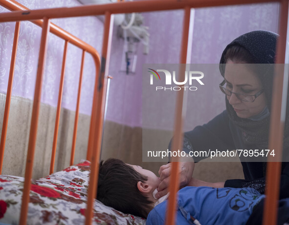 An Iranian mother takes care of her 9-year-old son with autism who is infected by COVID-19 as well, at a new coronavirus disease ward in a c...