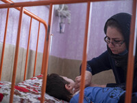 An Iranian mother takes care of her 9-year-old son with autism who is infected by COVID-19 as well, at a new coronavirus disease ward in a c...