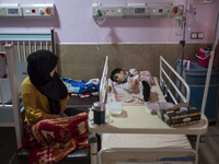 An Iranian mother sits next to her 9-year-old son who is infected by COVID-19, at a COVID-19 ward in a children hospital in the holy city of...