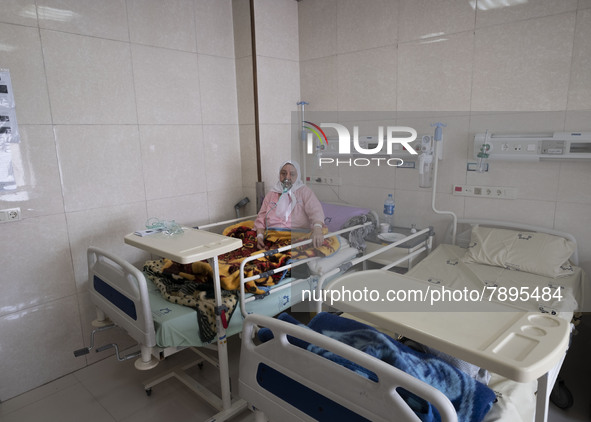 An Iranian elderly woman who is infected by COVID-19 uses oxygen while sitting on a hospital bed at a COVID-19 ward in a hospital in the hol...