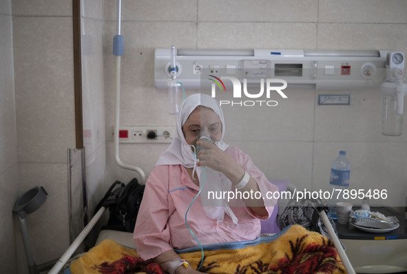 An Iranian elderly woman who is infected by COVID-19 uses oxygen while sitting on a hospital bed at a COVID-19 ward in a hospital in the hol...