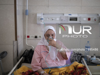 An Iranian elderly woman who is infected by COVID-19 uses oxygen while sitting on a hospital bed at a COVID-19 ward in a hospital in the hol...