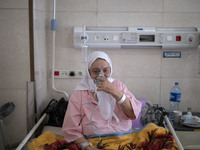 An Iranian elderly woman who is infected by COVID-19 uses oxygen while sitting on a hospital bed at a COVID-19 ward in a hospital in the hol...